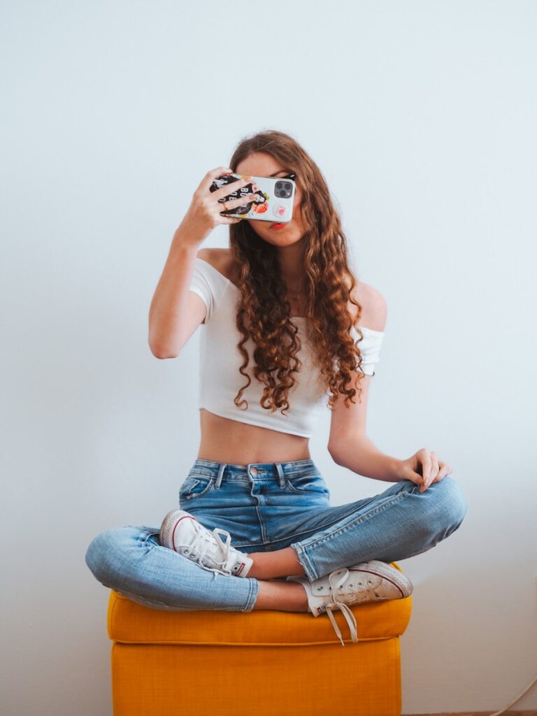 woman in pink long sleeve shirt and blue denim jeans sitting on white floor blogging
